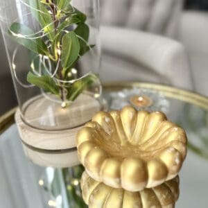 A gold candle holder sitting on top of a glass table.