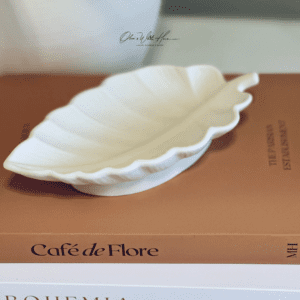 A white leaf shaped dish on top of a book.