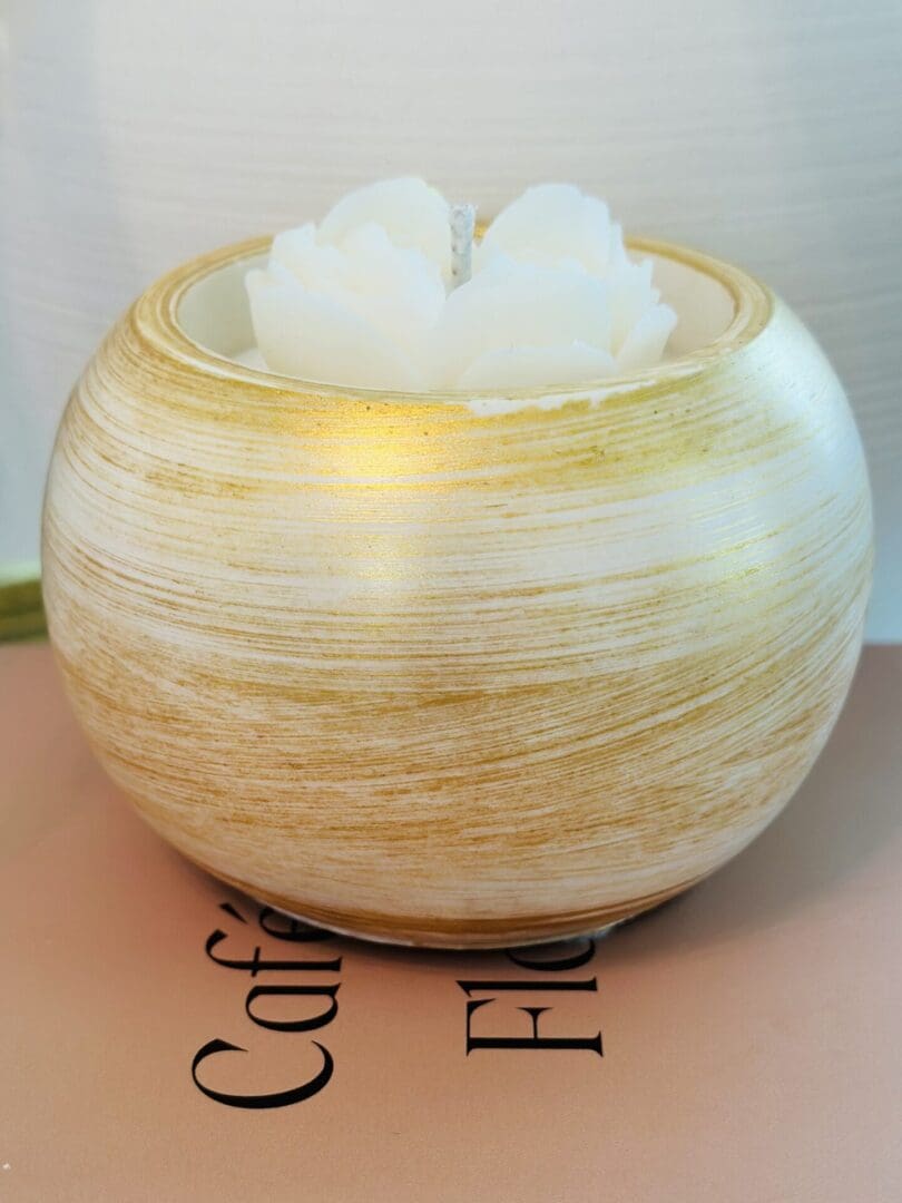 Golden round candle with floral design.